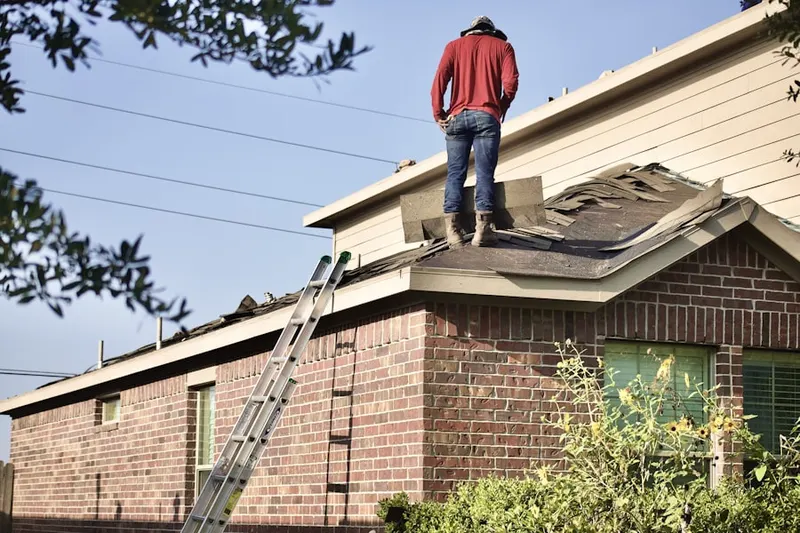 Professional roofer working on a residential roof in West Kingston